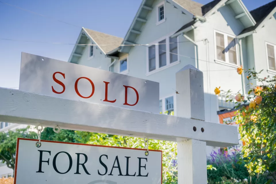 White house with For Sale and SOLD sign